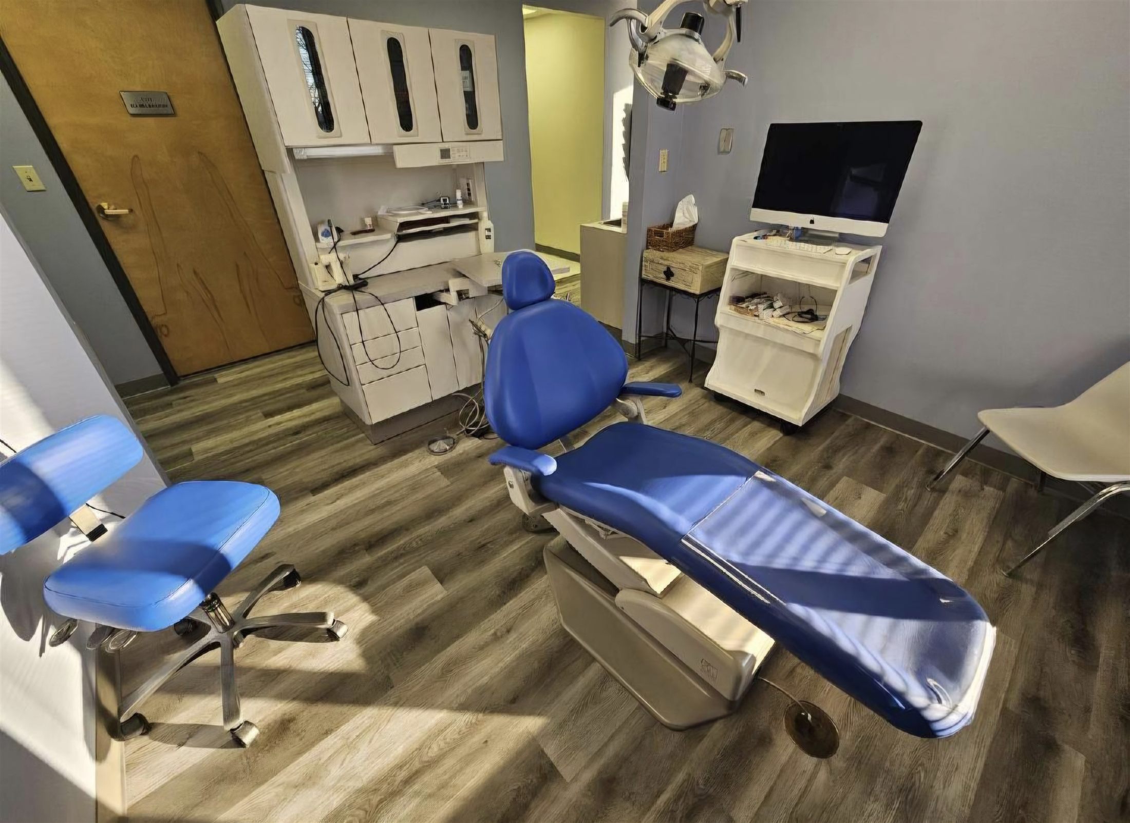 Operatory before equipment removal: dental chair, overhead light, delivery cart, stools, and monitor in place